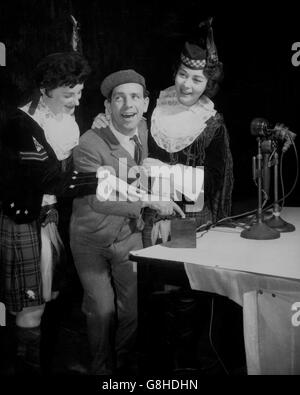 Il comico Norman Wisdom è aiutato da due membri del Dagenham Girl Pipers - caporale di 21 anni Joan Lee (l) e dal drum Major Ann Bechellier - mentre inizia il 7° Premium Bonds disegnare da telecomando presso l'Odeon Cinema, Oxford Street, Manchester. Quando Norman Wisdom ha premuto il pulsante, 'Ernie', il selettore elettronico del robot, è entrato in azione presso l'ufficio Premium Bonds di Lytham St Annes, Lancashire, per scegliere i vincitori di 6,995 premi. *NEG è corrotto. Acquisito dal contatto. Foto Stock