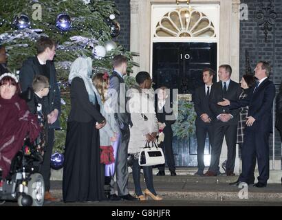 Il primo ministro David Cameron (a destra) assiste all'accensione delle luci degli alberi di Natale di Downing Street di Ted McCaffrey (quinta a sinistra), 8, su Downing Street, Londra. Foto Stock