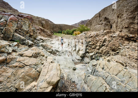 Donna che cammina in un fiume asciutto in un Wadi, montagne Hajar degli Emirati Arabi Uniti, Medio Oriente, una destinazione di viaggio Foto Stock