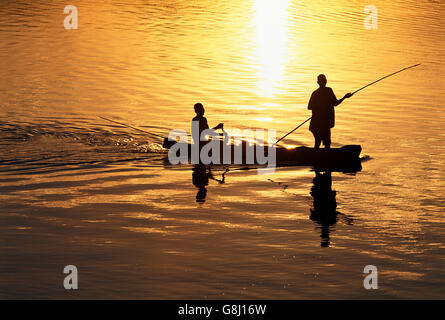 I pescatori sulla barca da pesca durante il tramonto, Silhouette, Fiume Luangwa, Zambia. Foto Stock