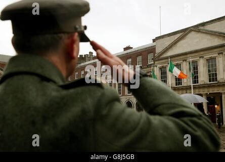 Un membro delle forze di difesa irlandesi saluta la bandiera nazionale che è stata fatta volare dal GPO su o'Connell Street durante la ribellione, come il primo grande evento a segnare il centenario della rivolta del 1916 si svolge al Castello di Dublino in Irlanda. Foto Stock