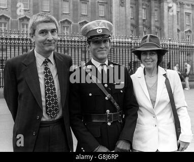 Tenente Keith Mills, Royal Marines, a Buckingham Palace per essere decorato con la distinta Croce di Servizio. È accanto al padre Alan (l) e ad un amico, Sheena Humphreys. Il distacco di LT Mills di Marines ha condotto la resistenza all'invasione argentina sulla dipendenza delle Falklands della Georgia del Sud. Foto Stock