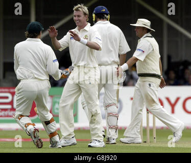 Il brett Lee dell'Australia (secondo a sinistra) celebra la presa del wicket dell'Inghilterra Kevin Pietersen come Shane Warne (R) gli dà un tocco mentre lascia il campo durante il primo giorno.