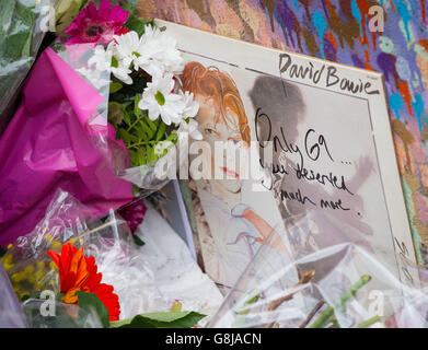 Tributi sono partiti ad un murale del musicista David Bowie, a Brixton, a sud di Londra, dopo l'annuncio di questa morte ieri. Foto Stock