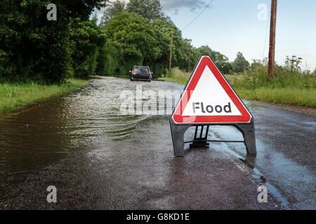 County road in Essex di allagata strada chiusa a causa di forte pioggia con vettura bloccato nel mezzo della strada Foto Stock