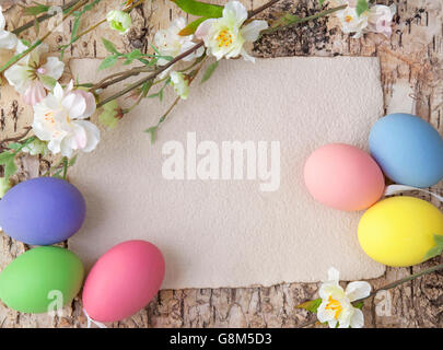 Uova di Pasqua e nota vuota su sfondo di legno Foto Stock