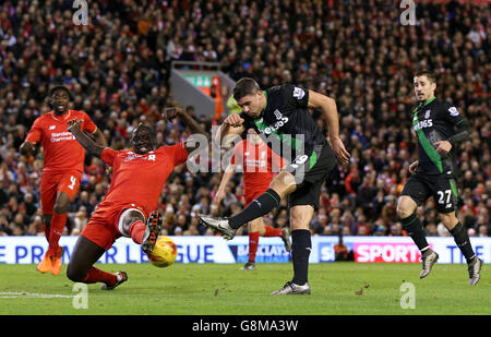 Il Mamadou Sakho di Liverpool (a sinistra) blocca un colpo da Jonathan Walters di Stoke City durante la Capital One Cup, semifinale, seconda tappa ad Anfield, Liverpool. Foto Stock