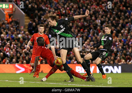 Mamadou Sakho di Liverpool (a sinistra) e Peter Crouch di Stoke City combattono per la palla durante la Capital One Cup, semifinale, seconda tappa ad Anfield, Liverpool. Foto Stock