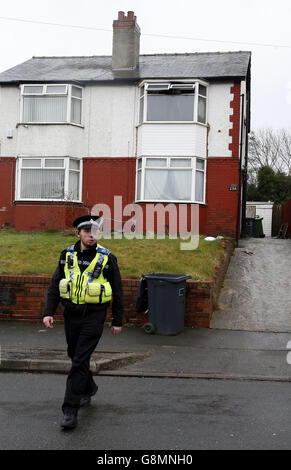 Un addetto al supporto della comunità di polizia fuori dalla casa di Alder Street, Huddersfield, dove due ragazzi credevano di essere di due e tre anni sono morti dopo un incendio della casa. Foto Stock