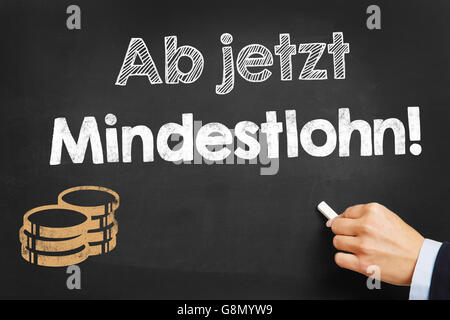 Scrive a mano in tedesco 'Ab jetzt Mindestlohn!" (salario minimo ora!) sulla lavagna Foto Stock