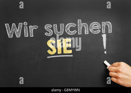 Scrive a mano in tedesco "Wir suchen SIE!' (abbiamo ware guardando il vostro VOI!) sulla lavagna Foto Stock