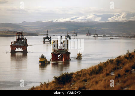 La piattaforma petrolifera Stena Spey è spostata con le barche di rimorchiatore tra gli altri carri che sono stati lasciati nel Cromarty Firth vicino Invergordon nelle Highlands della Scozia. Le piattaforme di perforazione sono state accatastate nel Cromarty Firth mentre i prezzi del petrolio continuano a diminuire, avendo un impatto importante sull'industria petrolifera del Mare del Nord del Regno Unito, lasciando migliaia di persone fuori lavoro. Foto Stock