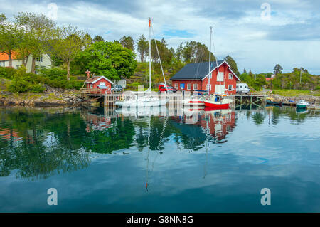 Costruzioni di legno, porto con barche e riflessioni a Kabelvåg Isole Lofoten in Norvegia Foto Stock