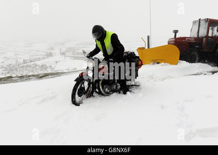 Il classico appassionato di motociclette David Carrick attraversa le Yorkshire Dales sulla strada per Dent per un rally, mentre le profonde nevicate coprono le cime dei Pennine. Foto Stock