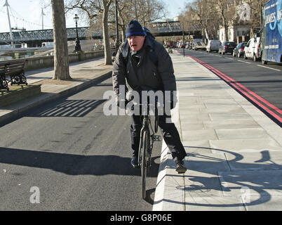Il sindaco di Londra Boris Johnson arriva sulla sua bici per interviste ai media su parte della East-West Cycle Superhighway, lungo Victoria Embankment a Londra. Foto Stock