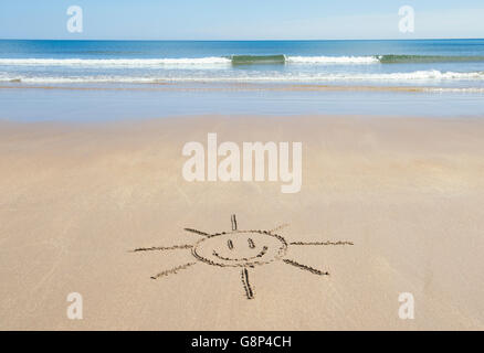 Smiley face sun disegno su una spiaggia. Regno Unito Foto Stock