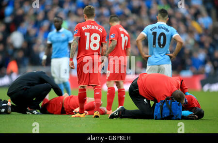 Emre Can di Liverpool (a sinistra) e Mamadou Sakho (a destra) vengono trattati in campo dopo uno scontro di teste durante la finale della Capital One Cup al Wembley Stadium di Londra. Foto Stock