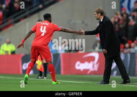 Il Kolo Toure di Liverpool (a sinistra) scuote la mano del manager Jurgen Klopp mentre viene in sostituzione del Mamadou Sakho (non raffigurato) durante la finale della Capital One Cup al Wembley Stadium di Londra. Foto Stock