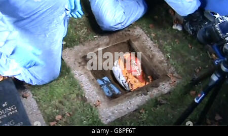 Immagine catturata da un filmato emesso dalla polizia metropolitana di Daniel Jones che accompagna la polizia in un cimitero di Londra del nord, dove una borsa di plastica contenente vari oggetti di gioielleria è stata recuperata da sotto una pietra commemorativa, Come cinque uomini coinvolti nel &Pound;14 milioni di Hatton Garden Jewelry raid sono stati incarcerati per un massimo di sette anni, mentre un sesto è stato dato una sentenza sospesa. Foto Stock