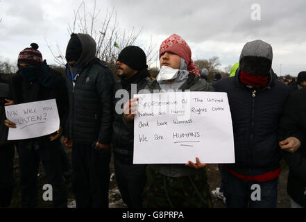 I migranti protestano mentre continuano le demolizioni nel campo migrante di Calais, noto come la giungla, nella Francia settentrionale. Foto Stock