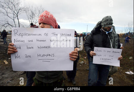 I migranti protestano mentre continuano le demolizioni nel campo migrante di Calais, noto come la giungla, nella Francia settentrionale. Foto Stock