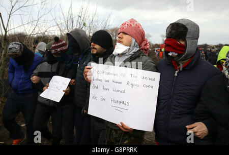 I migranti protestano mentre continuano le demolizioni nel campo migrante di Calais, noto come la giungla, nella Francia settentrionale. Foto Stock