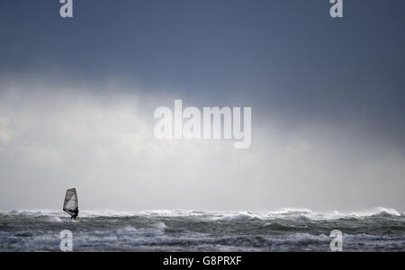 Un windsurfer corre le acque aspro al largo di West Wittering Beach nel Sussex occidentale, in quanto l'Ufficio MET ha emesso avvertenze gialle "BE aware" per neve e ghiaccio per gran parte dell'Inghilterra settentrionale e del Galles settentrionale, della Scozia e dell'Irlanda del Nord, con un massimo di 5 cm previsti in molti luoghi, aumento fino a 10 cm su un terreno più alto. Foto Stock