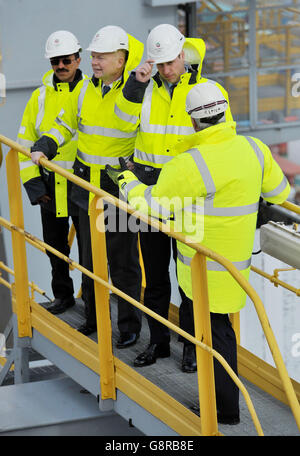 Il Duca di Cambridge (seconda a destra) tiene sul suo elmetto mentre una raffica di vento lo cattura mentre si trova su un gantry in cima ad una delle gru di container della nave, con il presidente del DP Sultan Ahmed Bin Sulayem (a sinistra), Lord Hague (seconda a sinistra) e il CEO del DP Simon Moore, Durante una visita al DP World's London Gateway, porto dei container a Stanford-le-Hope, Essex. Foto Stock