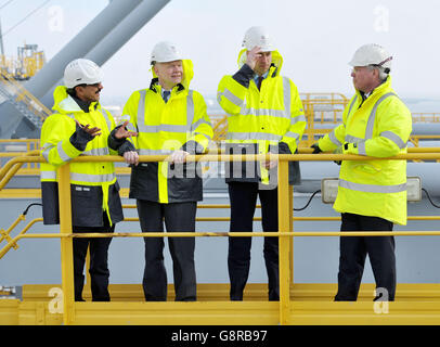 Il Duca di Cambridge (seconda a destra) tiene sul suo elmetto mentre una raffica di vento lo cattura mentre si trova su un gantry in cima ad una delle gru di container della nave, con il presidente del DP Sultan Ahmed Bin Sulayem (a sinistra), Lord Hague (seconda a sinistra) e il CEO del DP Simon Moore, Durante una visita al DP World's London Gateway, porto dei container a Stanford-le-Hope, Essex. Foto Stock