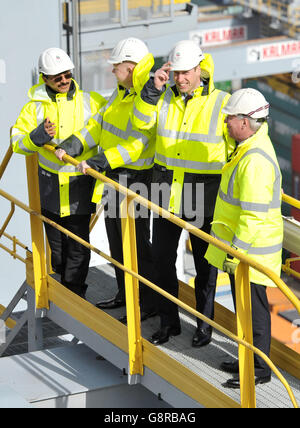 Il Duca di Cambridge (seconda a destra) tiene sul suo elmetto mentre una raffica di vento lo cattura mentre si trova su un gantry in cima ad una delle gru di container della nave, con il presidente del DP Sultan Ahmed Bin Sulayem (a sinistra), Lord Hague (seconda a sinistra) e il CEO del DP Simon Moore, Durante una visita al DP World's London Gateway, porto dei container a Stanford-le-Hope, Essex. Foto Stock