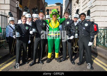 Un uomo vestito come un leprechaun pone per una foto con i membri della Coppell High School Marching Band davanti al Sindaco di Londra St Patrick's Day Parade and Festival a Londra. Foto Stock