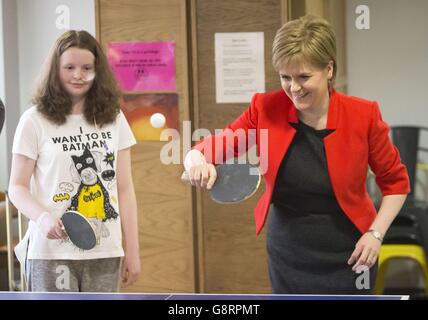 Il primo ministro Nicola Sturgeon gioca a ping-pong con il paziente Erin Campbell durante una visita al Royal Hospital for Sick Children di Glasgow, poiché ha affermato che i maggiori guadagnatori della Scozia non riceveranno una riduzione fiscale proposta per il resto del Regno Unito, una mossa che potrebbe aumentare di &sterline;1.2 miliardi di euro per i servizi pubblici a nord del confine. Foto Stock