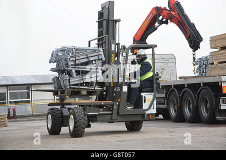 Un camion-montato carrello elevatore scarica ponteggi attrezzature da un pianale, autoarticolato rimorchio Foto Stock