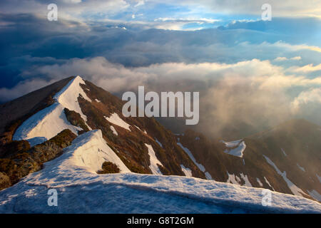 Inizio della primavera nelle montagne dei Carpazi, neve.nebbia illuminata di rosso e di giallo sole. buona di nebbia dopo la tempesta Foto Stock