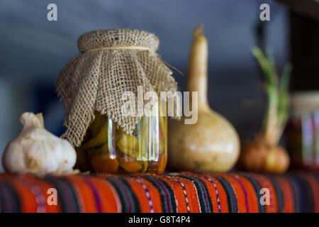 In casa conserve di peperoncino sul vecchio ripiano rustico. Cetrioli e pomodori aglio cipolla e altri. Foto Stock