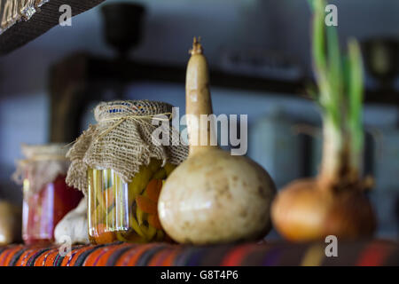 In casa conserve di peperoncino sul vecchio ripiano rustico. Cetrioli e pomodori e altri. Foto Stock