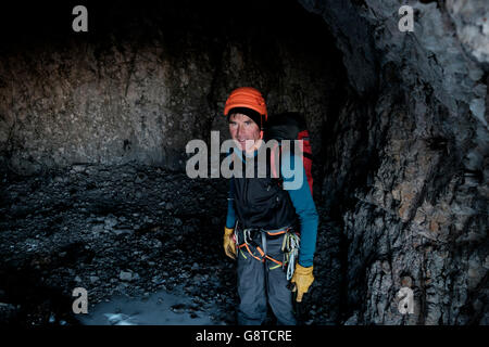 Guida di montagna con il casco e zaino in piedi in grotta Foto Stock