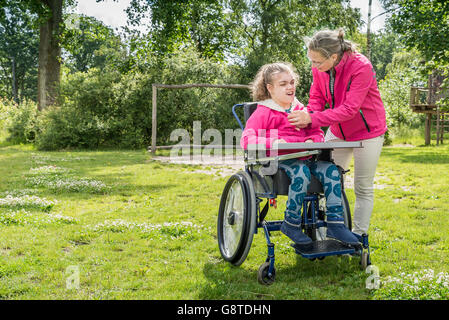 Un disabile su sedia a rotelle rilassarsi con l aiuto di un volontario lavoratore di cura Foto Stock
