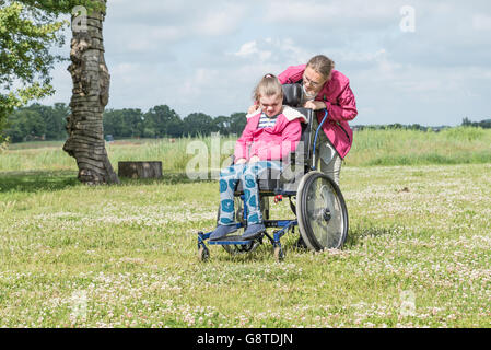 Un disabile su sedia a rotelle rilassarsi con l aiuto di un volontario lavoratore di cura Foto Stock