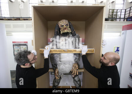 Operai che gestiscono un modello di replica a grandezza naturale del Predator, Che fa parte dell'installazione dell'artista Simon Denny The Personal Effects of Kim Dotcom, (2013-), durante un'anteprima stampa di Emotional Supply Chain - una mostra di gruppo di artisti internazionali 'ispirati alle identità digitali che ritrattiamo su piattaforme come Facebook e Instagram' - alla Zabludowicz Collection, Londra. Foto Stock