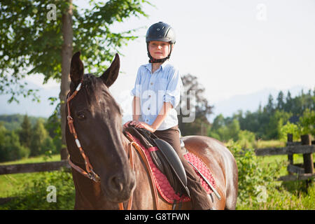 Ragazzo su ranch impara a guidare un cavallo Foto Stock