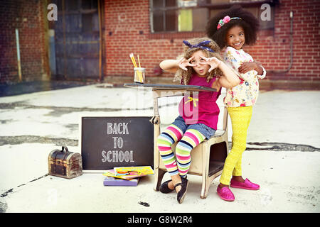 Due bambini in posa per il ritorno a scuola ad con un background urbano Foto Stock