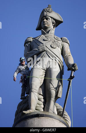 Luke Jones in cima alla colonna di Nelson in Trafalgar Square a Londra dopo che lui e un altro attivista di Greenpeace hanno scalato il punto di riferimento come parte di una mattinata di proteste per evidenziare l'inquinamento atmosferico in Gran Bretagna. Foto Stock