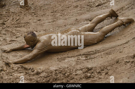 Un partecipante scivola sul fango durante l'evento "King of the Swingers" Tough Mudder London West alla Culden FAW Estate vicino a Henley-on-Thames. Foto Stock