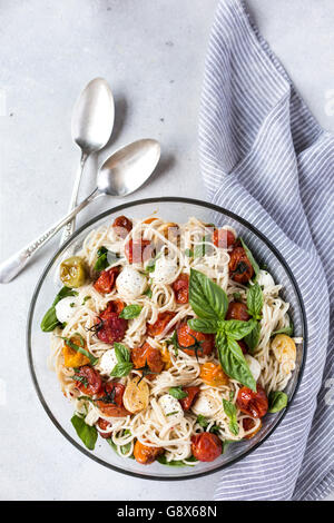 Una grande ciotola di caprese spaghetti con pomodori arrostiti, basilico fresco e mozzarella è fotografata dalla vista dall'alto. Foto Stock