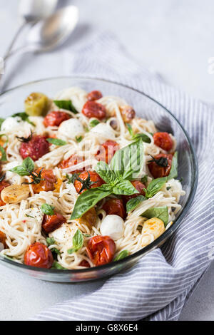 Una grande ciotola di caprese spaghetti con pomodori arrostiti, basilico fresco e mozzarella è fotografato dal vista frontale. Foto Stock