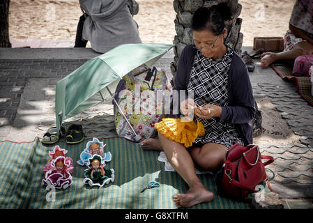 Donna anziana maglieria bambole di lana per bambini in vendita su una strada in Thailandia. S. E. Asia Foto Stock