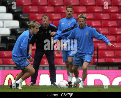 Phil Neville (L) dell'Inghilterra passa a David Beckham (R) come assistente allenatore Steve McClaren (secondo da sinistra) e Luke Young guarda su durante una sessione di allenamento a Old Trafford, Manchester, venerdì 7 ottobre 2005. L'Inghilterra gioca l'Austria in un qualificatore di Coppa del mondo a Old Trafford domani. PREMERE ASSOCIAZIONE foto. Il credito fotografico dovrebbe essere: Martin Rickett/PA Foto Stock