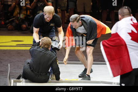 Il principe Harry aiuta Anna Hall Mayzik dopo che è caduto sopra mentre stava presentando una medaglia d'argento ad un atleta tedesco ai giochi di Invictus 2016 all'ESPN Wide World of Sports a Orlando, Florida. Foto Stock