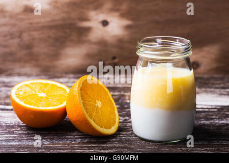 Deliziosa casa arancione organico frullati in un vasetto di vetro con un fresco e fettine di arancia sul tavolo di legno Foto Stock